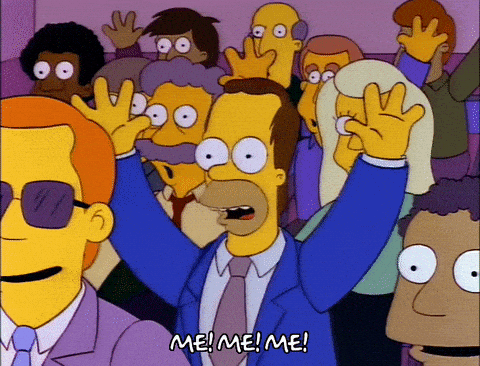 A looping GIF of a young Homer Simpson in a crowd of people all putting their hands up shouting "Me! Me! Me!"